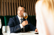 © JustLife - Handsome businessman dressed in the suit drinking wine. Businessman and businesswoman enjoying in the restaurant.