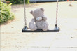 © kittyfly - gray teddy bear sitting alone on swing, concept of loss of parents, loneliness of children, caring for orphans