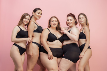 Wall Mural - Loves herself and feels good. Portrait of beautiful young women with different shapes posing on pink background. Happy female models. Concept of body positive, beauty, fashion, style, feminism