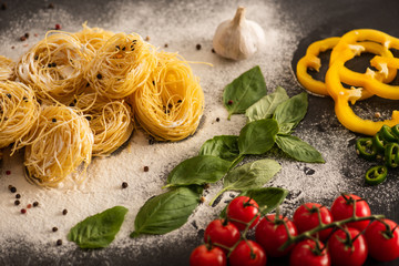 Wall Mural - raw Italian Capellini with vegetables on flour on black background