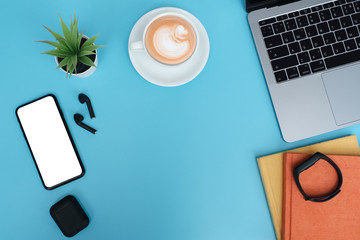Wall Mural - Workspace back to school and education concept on blue table desk background with laptop computer, blank screen phone and stack of book, earphone, green plant and coffee cup, flat lay with copy space