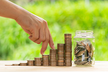 Investor business man finger walking on row of coins stack with blur green nature background. Money saving concept or Business growth concept.