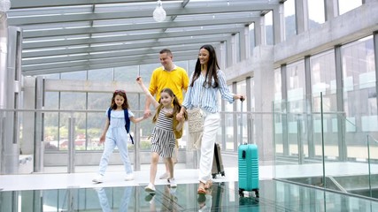 Wall Mural - Family with two children going on holiday, walking at the airport with luggage.