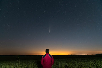 Wall Mural - silhouette of a man standing at night in a field outside the city. starry night sky with comet neowi