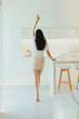 © Mirrorstudio - Young woman dancing in light kitchen with minimalistic design