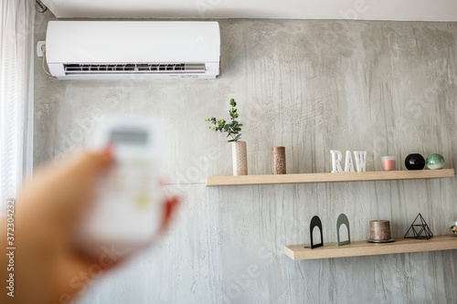 Cuadros en Lienzo Air conditioner inside the room with woman operating remote controller