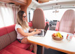© Jose Prieto - Mujer de mediana edad con gafas teletrabajando con su ordenador portátil en vacaciones desde su autocaravana a modo de oficina móvil