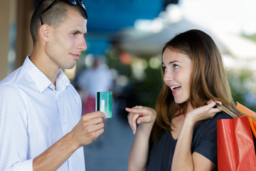 couple out shopping woman asking man for credit card