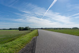 Fototapeta Na ścianę - Low angle shot of a empty road that disappears at the horizon in a rural landscape