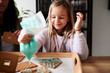 © Ivan Gener/Stocksy - Smiling child decorating a gingerbread house