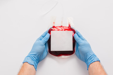 Sticker - cropped view of doctor holding blood donation package with blank label on white background
