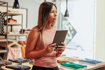 Wall Mural - Latin woman owner of small business. Entrepreneurial woman working in her clothing store.