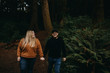 © Leah Flores/Stocksy - Couple Walking in Dark Woods Holding Hands