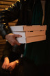 © Rowena Naylor Photography/Stocksy - Person carrying three takeaway pizza boxes at night