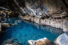 Natural Geothermal Hot Spring In The Cave Grjotagja, Iceland Blue Water And Colorful Lava Stones