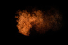 Orange Powder Explosion On Black Background. Colored Powder Cloud. Colorful Dust Explode. Paint Holi.