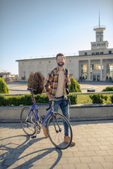 Attractive smiling man walking in city with bike