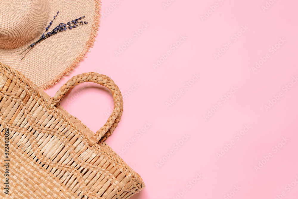 Straw hat and bag on color background