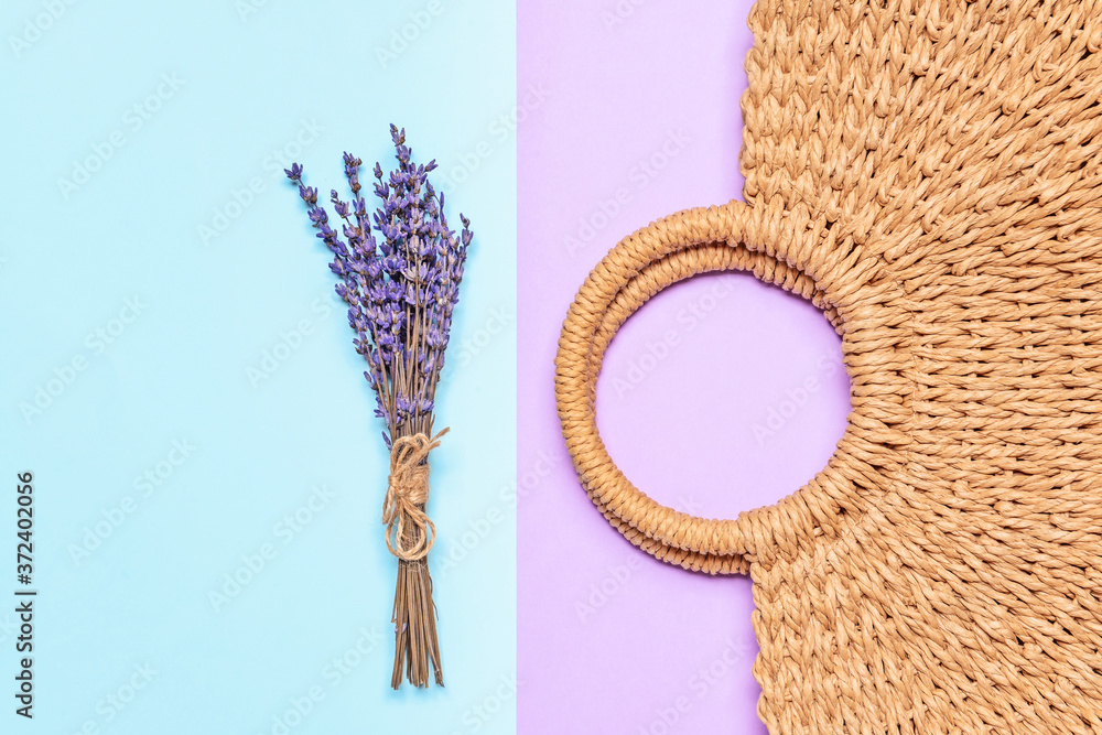 Straw bag with lavender on color background