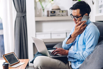 young smiling asian man relaxing using laptop computer working and video conference meeting at home.