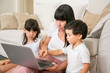© Mangostar - Mom teaching kids to use laptop, holding hand of little son and pressing keyboard button with boy finger. Medium shot. Parenthood and modern technology concept
