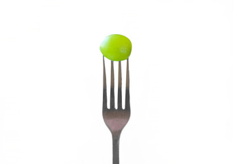 Grape berry on a fork. Diet and healthy food concept. Green grapes with fork on white isolated background