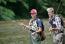 A Father And His Son Fly Fishing In Summer On A Beautiful Trout River With Clear Water
