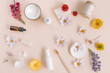 © Nina - White containers of beauty treatments, aromatherapy oil, organic soaps, eco friendly toothbrush, flower buds on beige background.
