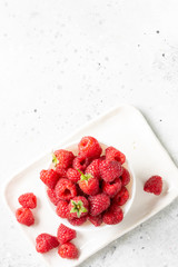 Raspberry berry. Raspberries in a white bowl on a light gray table. Fresh raspberries on a plate. Top view with space for text. Healthy diet