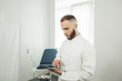 © Olha - A male gynecologist is alone in the office, holding a tablet and reading the test results. The concept of modern medicine