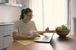 © stokkete - Woman sitting at the kitchen table and connecting with her laptop