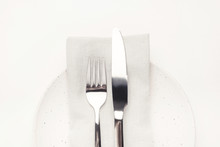Set Of Cutlery Knife And Fork, White Plate And Napkin On A White Wooden Table. Restaurant Or Cafe Concept.