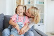 © AnnaStills - Young mother embracing her disabled child while they sitting on sofa in the room