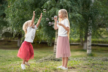 Two Sisters Blowing Soap Bubbles And Having Fun