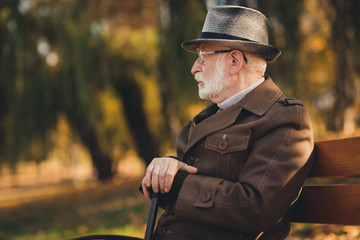 Canvas Print - Profile photo of retired old white hair gloomy grandpa street central park sit bench hold walk cane stick look frustrated contemplating think life past wear autumn glasses jacket hat outside