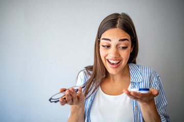 Wall Mural - Woman holds out glasses and contact lenses. The choice between contact lenses and glasses.  Woman holds out glasses and contact lenses. Myopia and eyesight problem concept.