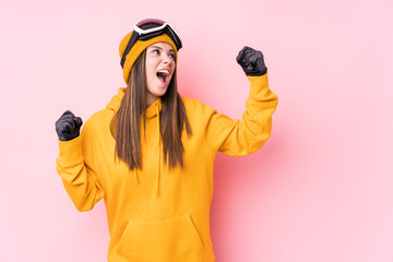 Wall Mural - Young caucasian skier woman isolated raising fist after a victory, winner concept.