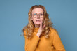 © Viktor Koldunov - Mature caucasian woman with hand beside mouth telling gossip or calling someone, studio shot on blue wall.