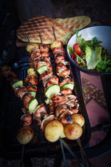 Poster - Freshly grilled meat and vegetable skewers with salad and flat bread on outdoor barbecue