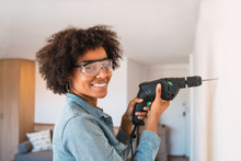 Afro Woman Drilling Wall With Electric Drill.