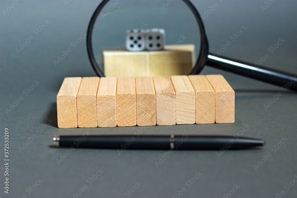 Nine wooden blocks are stacked in a single line with a fountain pen and ...
