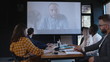© vadim_key - Team of diverse business people use projector for online web conference call with male boss coach at modern office.