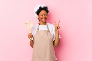 Wall Mural - Young african american cook woman showing number two with fingers.