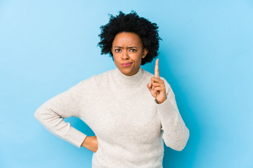 Wall Mural - Middle aged african american woman against a blue background isolated having an idea, inspiration concept.