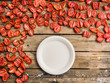 dry tomatoes on a wooden background and a disposable sugar cane plate