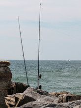 Two Fishing Poles Standing On A Rock Jetty Fishing At The Ocean