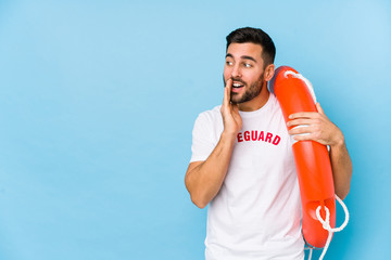 Wall Mural - Young handsome lifeguard man isoalted is saying a secret hot braking news and looking aside