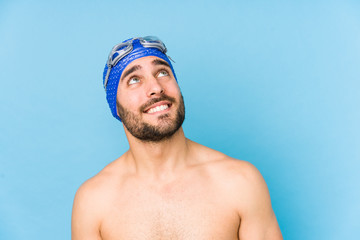 Wall Mural - Young handsome swimmer man isolated dreaming of achieving goals and purposes