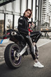 © Fxquadro - Hot looking girl in a black jacket sits on a purple motorbike with a red safety helmet