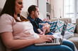 © Eva Blanco/Westend61 - Father carrying sleeping daughter while mother using laptop on sofa